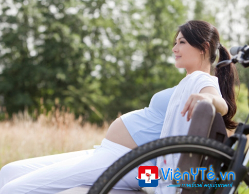 Pregnant woman sitting on bench with mountainbike next to her